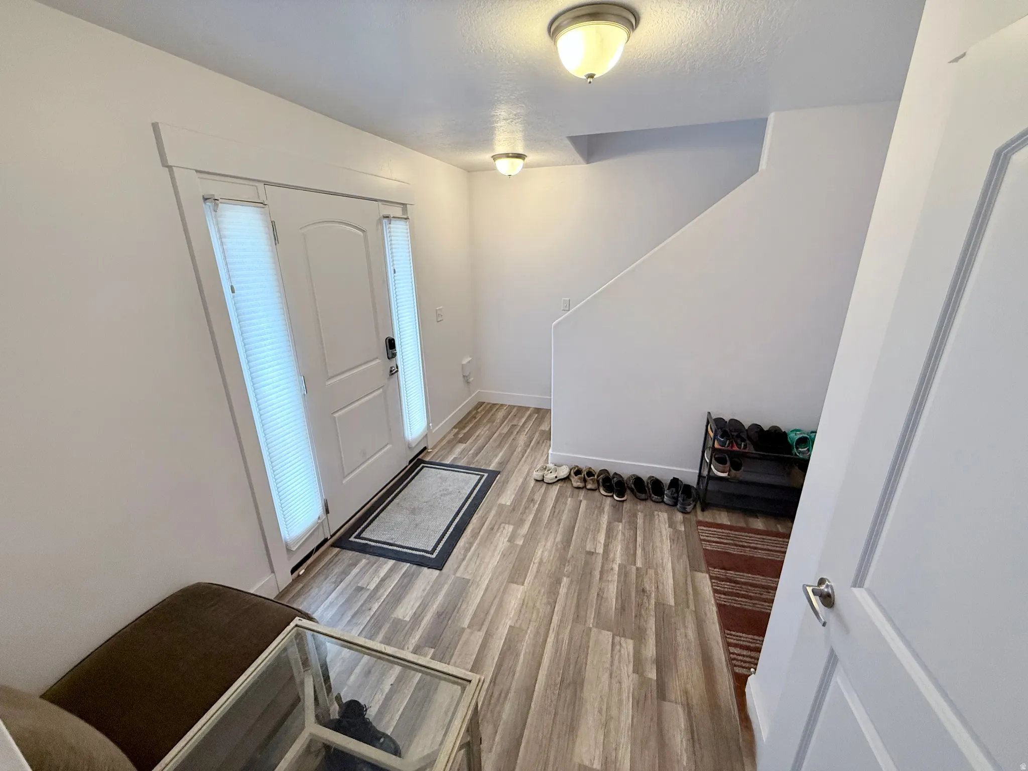 Entryway featuring a white paneled door with dual sidelights, wood-finish flooring, a neutral color palette, and flush-mount ceiling lights