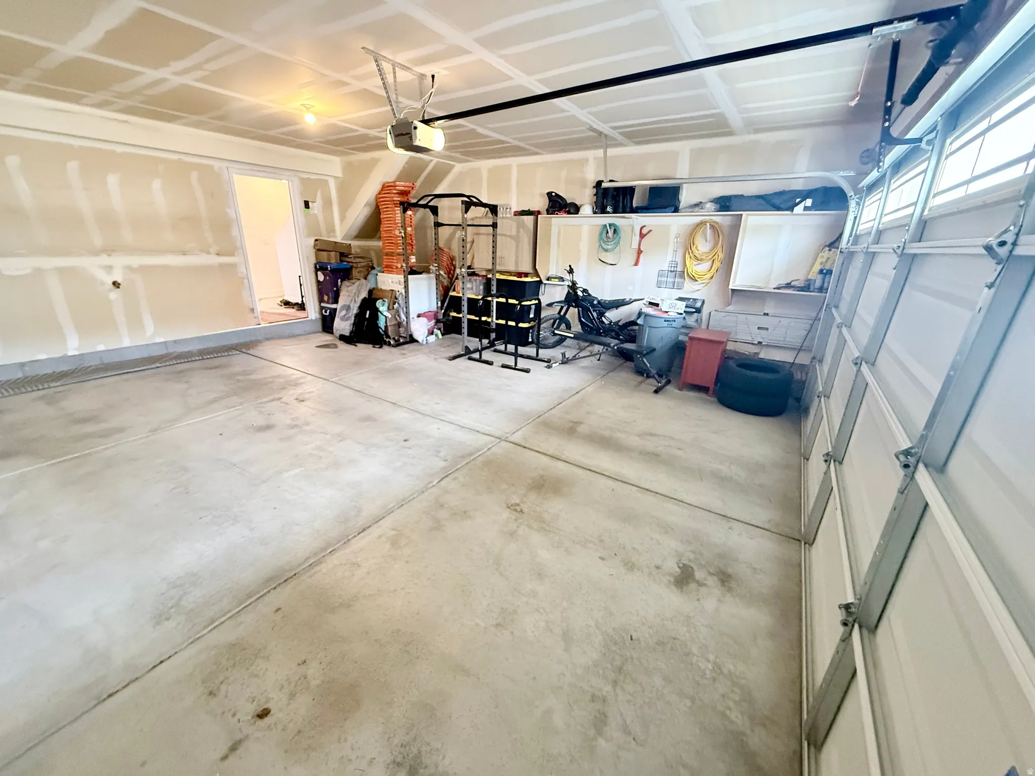 Spacious garage featuring a concrete floor, exposed drywall, and an overhead garage door opener