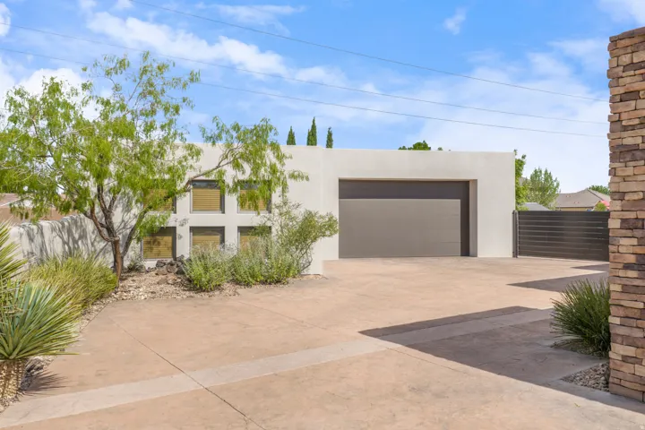 Modern stucco exterior with an integrated garage, a stamped concrete driveway, and a coordinated garage door
