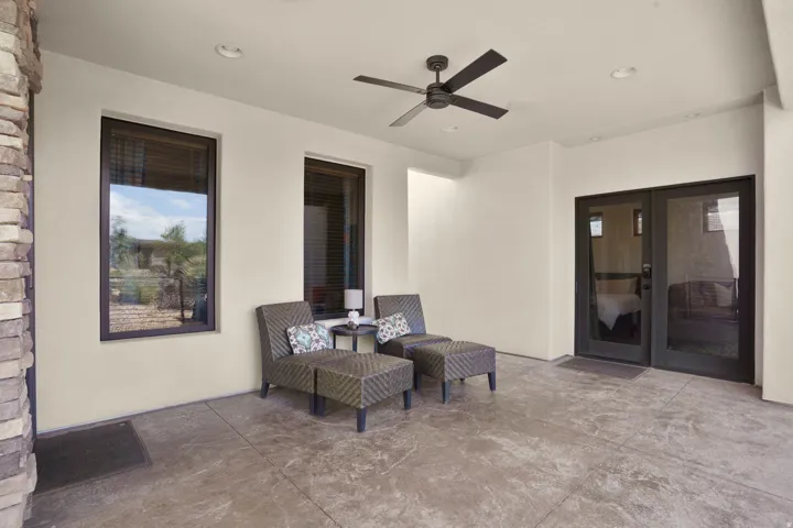 Covered patio with stamped concrete flooring, stacked stone column, and dual ceiling fans