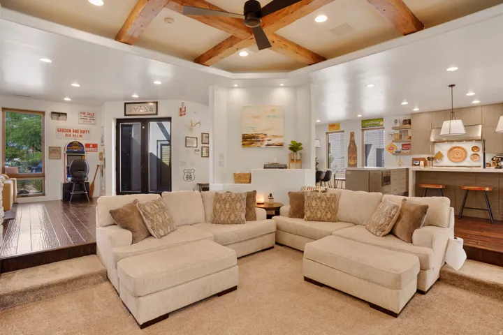 Exposed wood ceiling beams, recessed lighting, and a ceiling fan define this living space