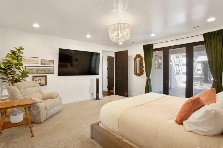 Bedroom featuring French doors opening to an outdoor patio, recessed lighting, and a decorative chandelier