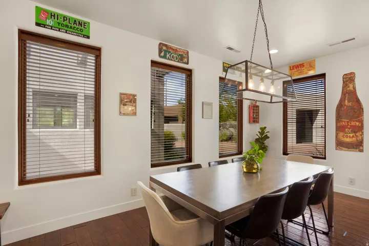 Dining area featuring dark wood-finish flooring, white walls, and multiple windows with wood frames and slatted blinds