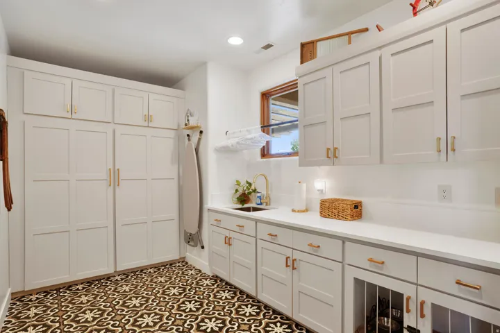 Laundry room with decorative floor tiling and extensive white cabinetry