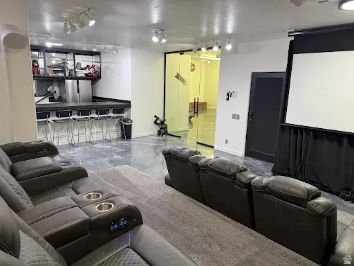 Entertainment space featuring a large projection screen, a built-in bar with seating, and track lighting