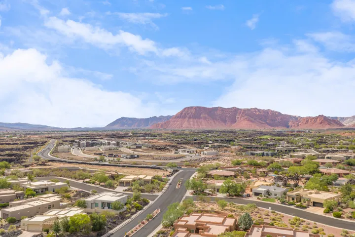Expansive aerial perspective showcasing a residential development with a red rock mountain backdrop
