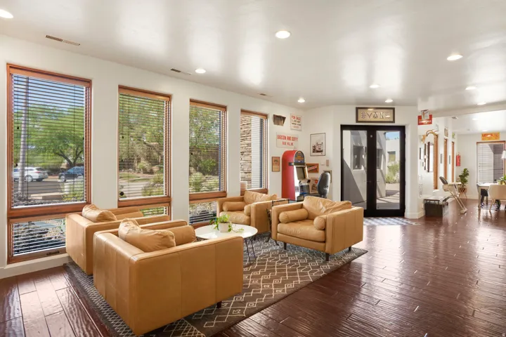 Spacious living area featuring rich wood-finish flooring, recessed lighting, and multiple large windows with wooden frames