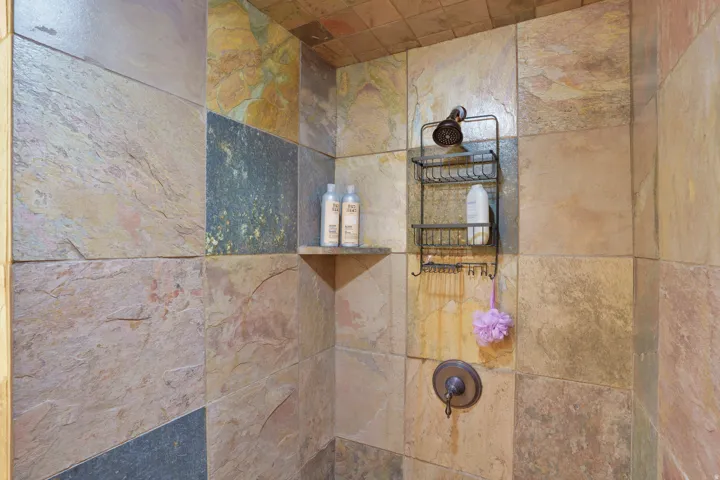 Shower featuring natural stone tile walls and ceiling