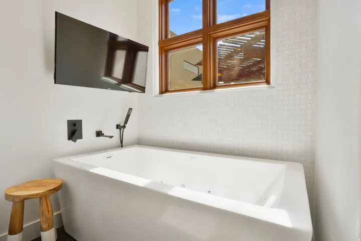 Freestanding soaking tub featuring matte black wall-mounted fixtures and a handheld shower