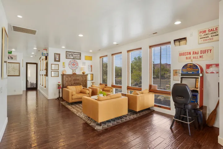 Spacious room featuring rich wood-finish flooring, recessed ceiling lighting, and multiple large windows with natural wood trim