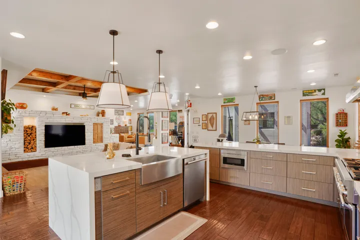 Kitchen featuring a waterfall-edge island with stainless steel farmhouse sink and integrated dishwasher