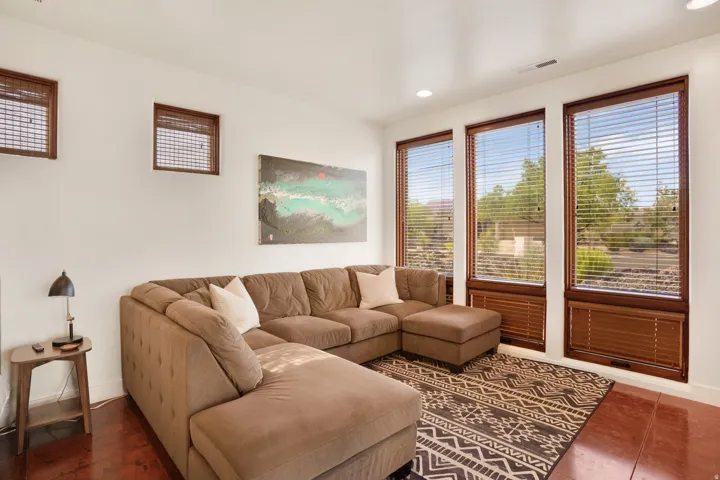 Living area featuring wood-finish flooring, recessed lighting, and large windows with blinds