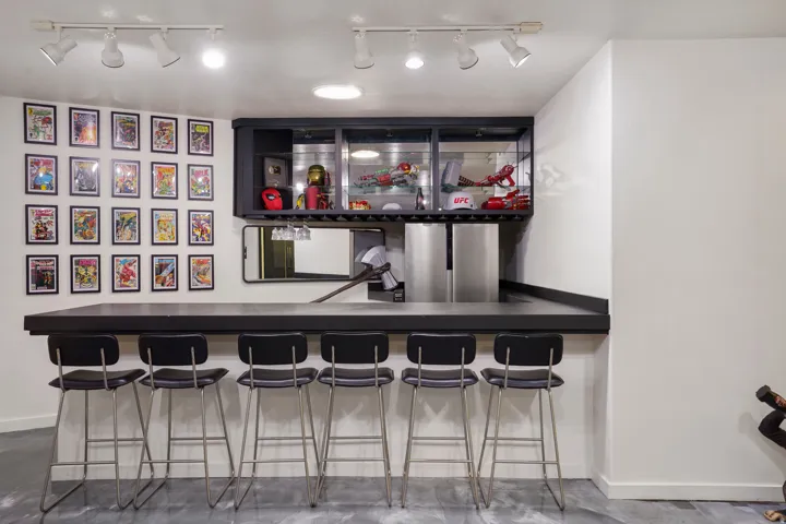 Integrated bar area featuring a dark countertop, built-in display cabinetry with glass fronts, and two stainless steel beverage refrigerators