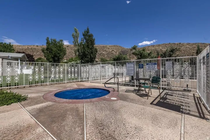 Outdoor spa with a concrete surround and a decorative metal fence