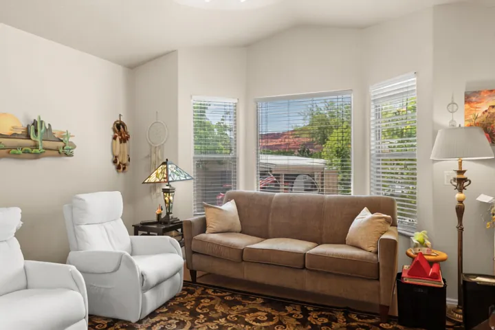 Vaulted ceiling with a flush-mount light fixture, corner windows, and horizontal blinds