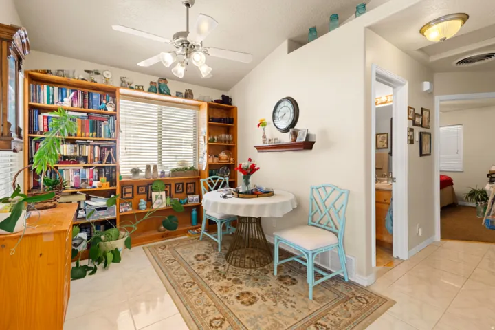 Vaulted ceiling with a ceiling fan, recessed wall niche, built-in shelving, and tile flooring