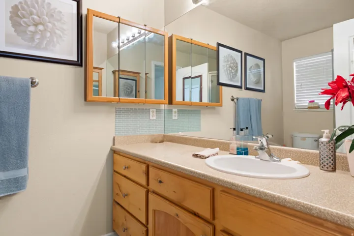 Vanity with wood-finish cabinetry, integrated sink, and light-toned countertop