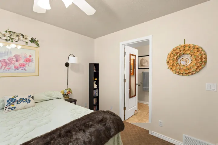 Ceiling fan, wall-mounted light fixture, built-in shelving, white trim, and tiled flooring visible through doorway