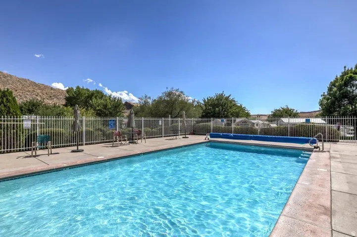 Outdoor swimming pool featuring a concrete deck and a white metal fence