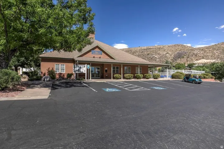 Clubhouse building with a prominent front entrance, adjacent parking lot, and mountain backdrop