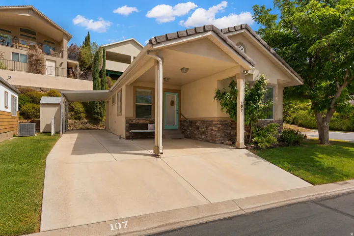 Exterior featuring stucco and stone facade, a covered carport, a light blue entry door, and a concrete driveway