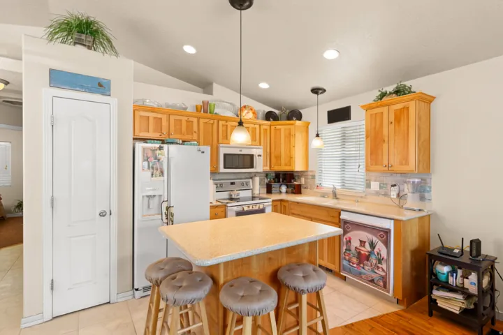 Kitchen featuring light-tone wood cabinetry, recessed lighting, pendant lighting, a kitchen island, and a tile backsplash