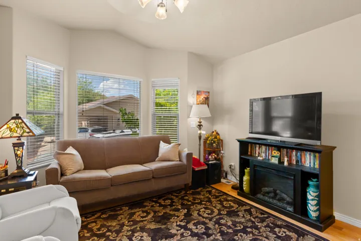 Living area with vaulted ceilings, multiple windows, wood-finish flooring, and a built-in media console with a fireplace
