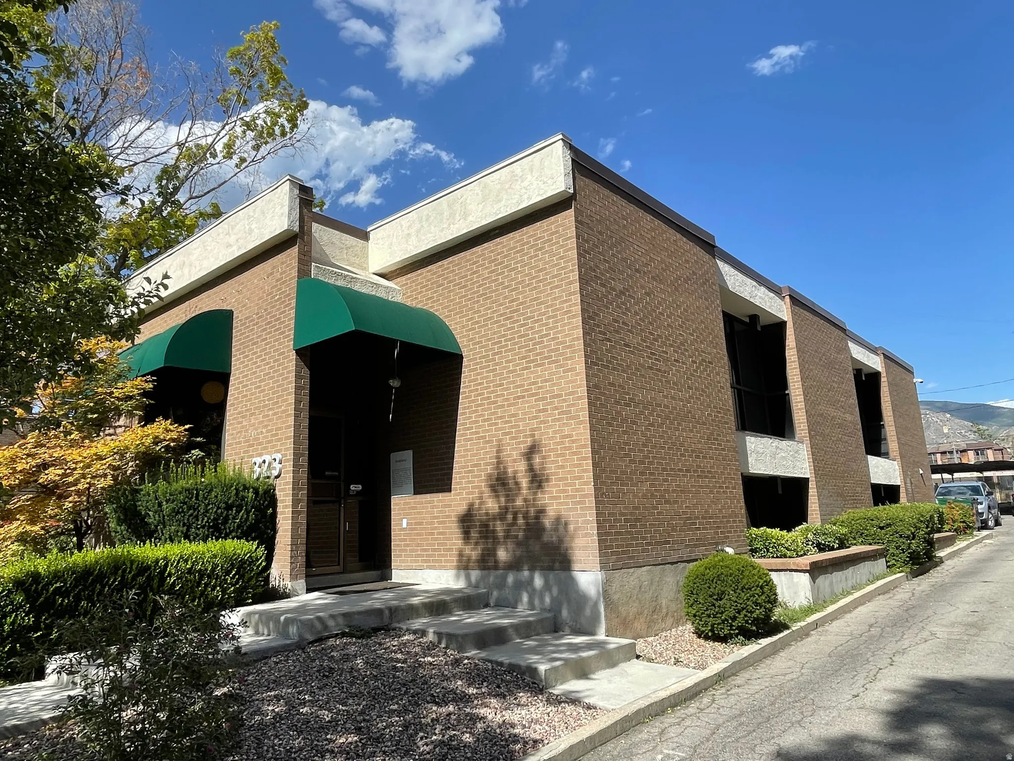 Brick exterior featuring green awnings and concrete stairs