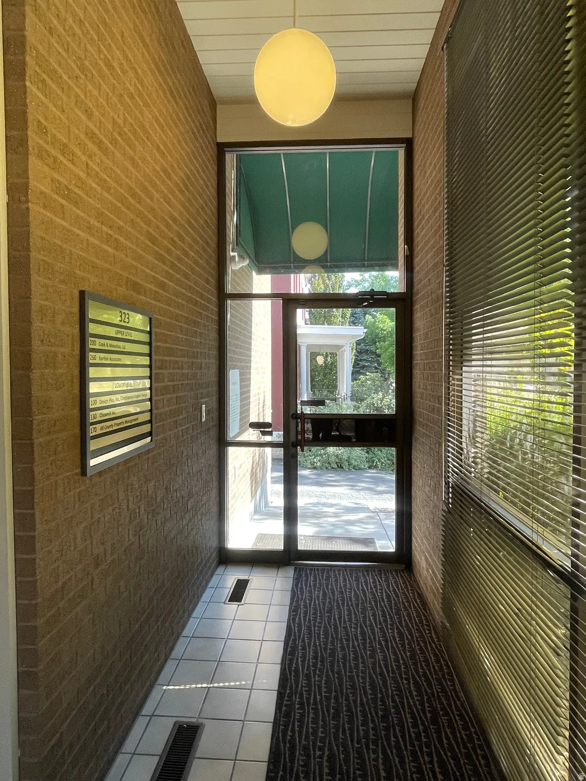 Entryway featuring a full-glass door, brick wall accents, and a spherical ceiling light fixture