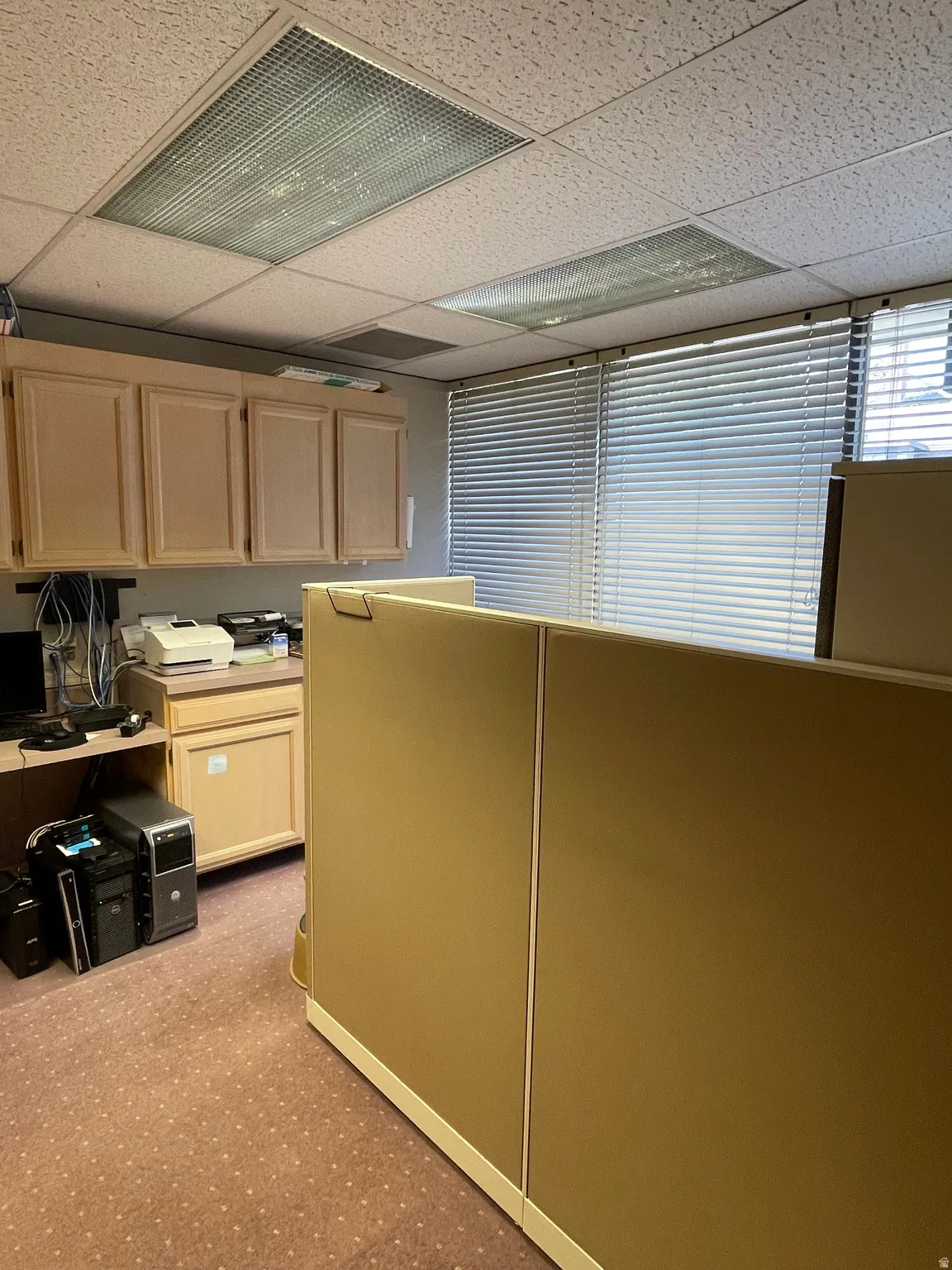 Interior office space featuring modular workstation dividers, built-in cabinetry, and horizontal blinds