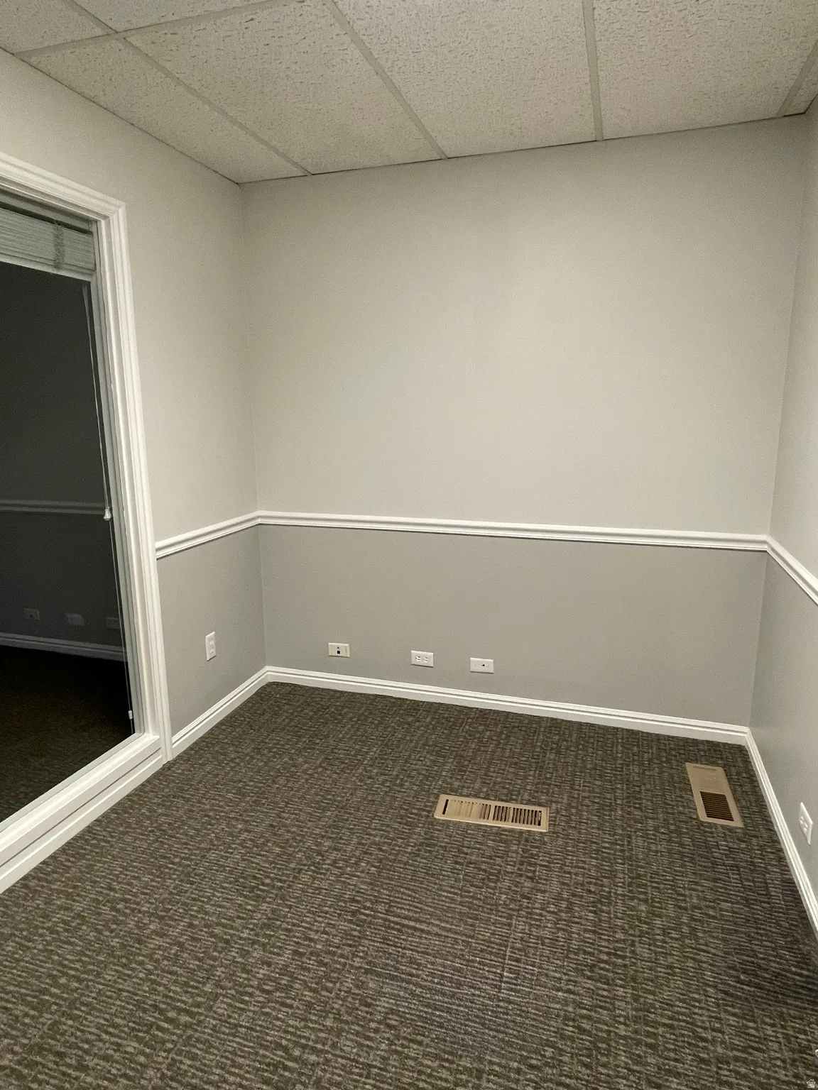 Neutral two-tone wall paint with white trim, accented by patterned carpet flooring