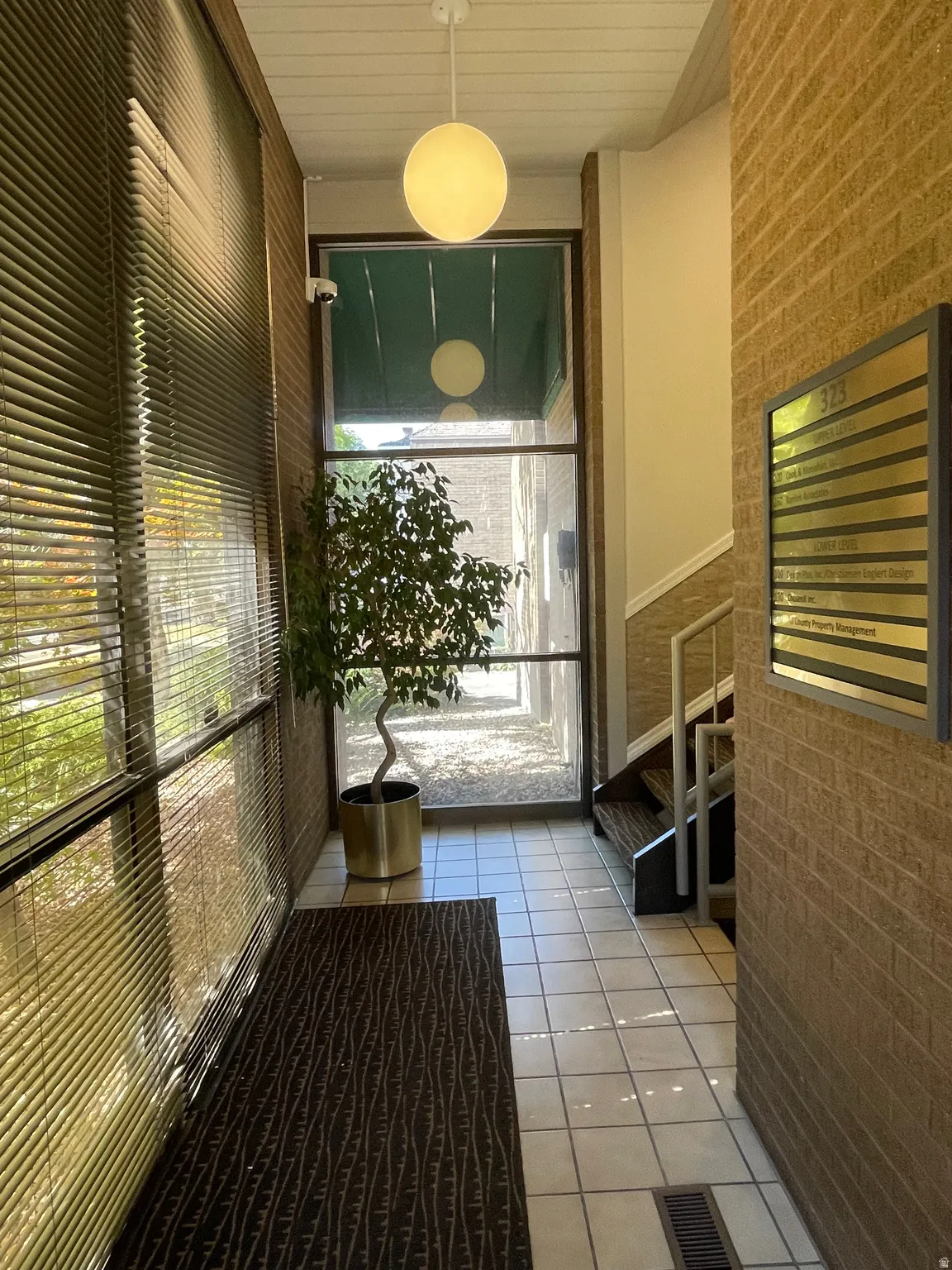 Entryway featuring light-toned square floor tiles and a brick-patterned wall