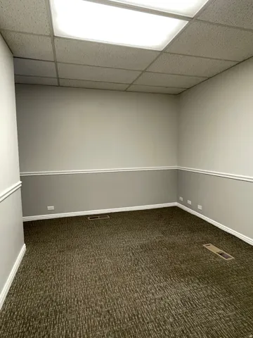 Carpeted interior space featuring neutral two-tone walls with chair rail molding and white baseboards