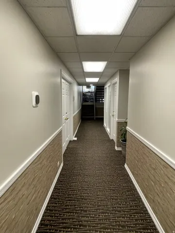 Carpeted hallway featuring a drop ceiling with recessed lighting