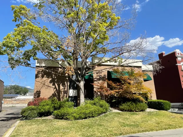Brick exterior with a mature tree, green awnings, and established landscaping