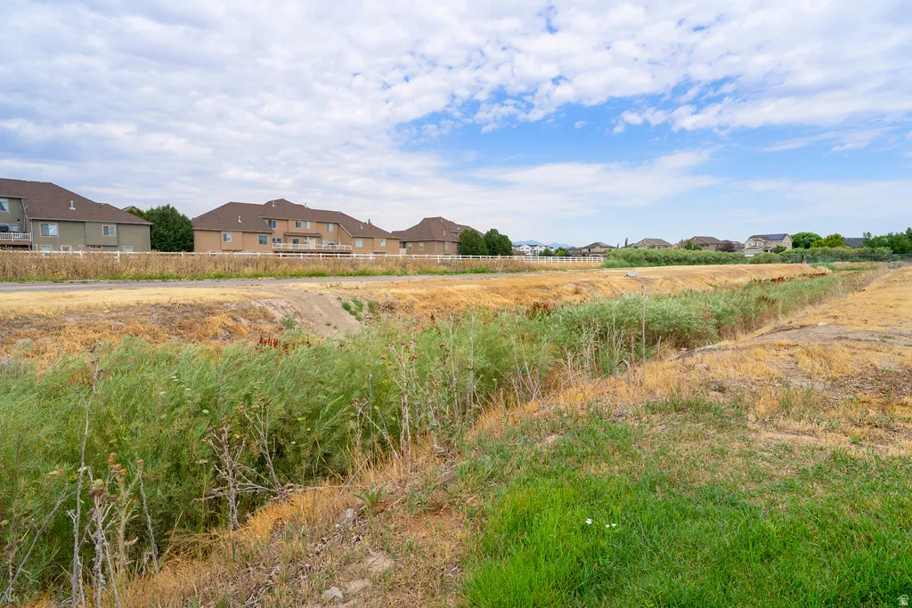 Expansive undeveloped land featuring natural vegetation and distant residential structures
