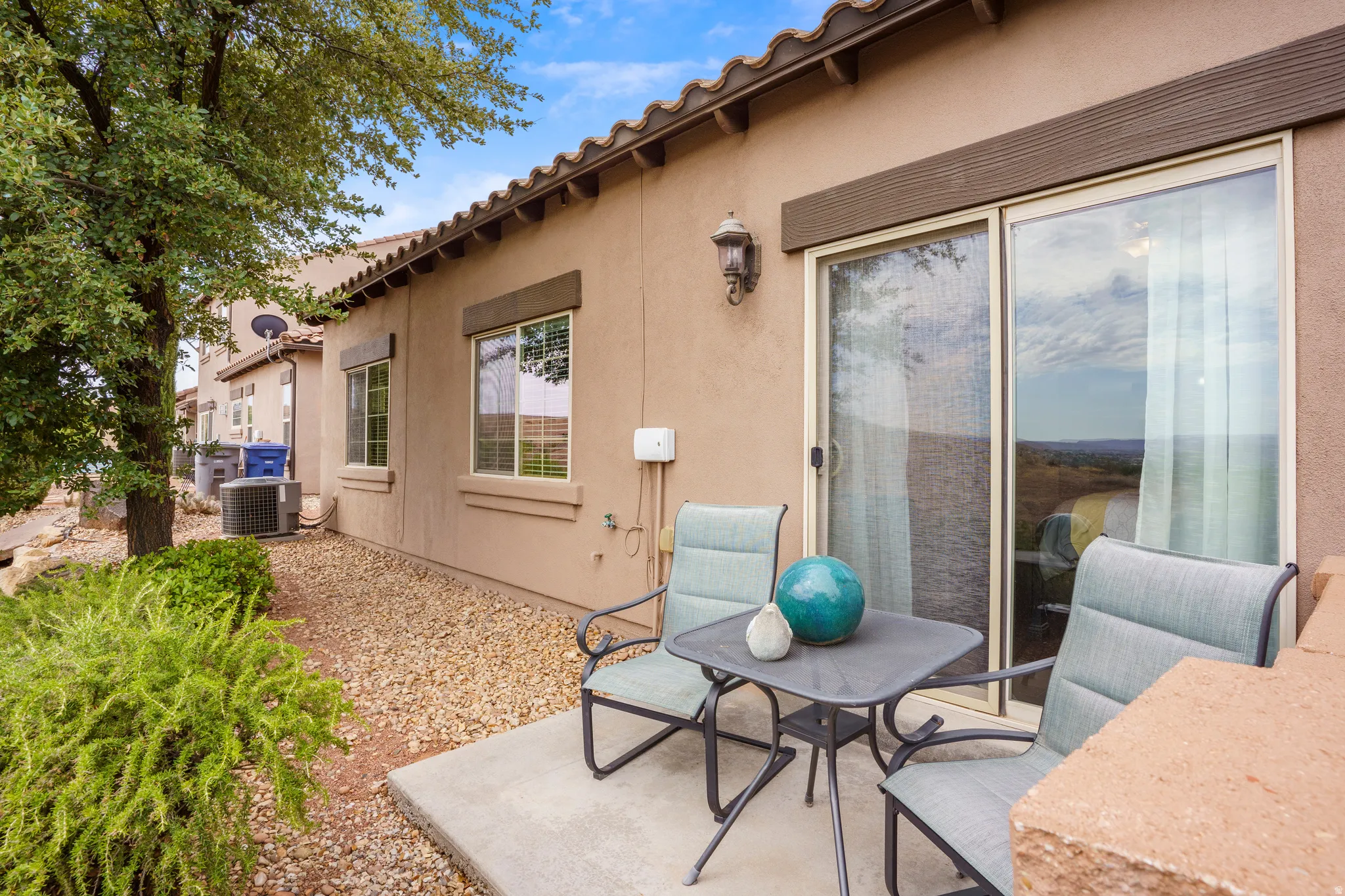 Patio area featuring a stucco exterior, concrete paving, and a sliding glass door