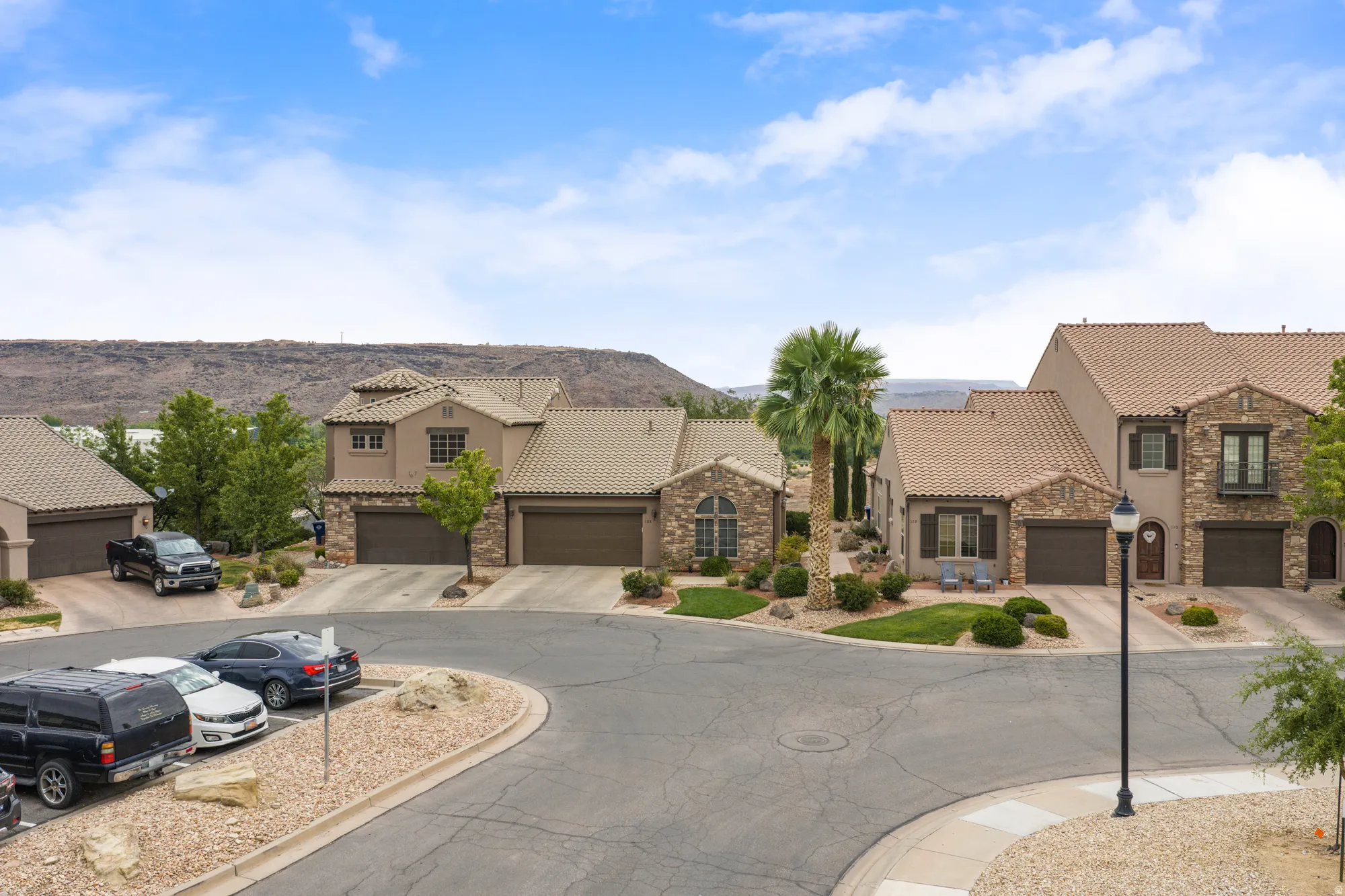 Mediterranean-style homes featuring stone and stucco exteriors, tile roofs, and attached garages