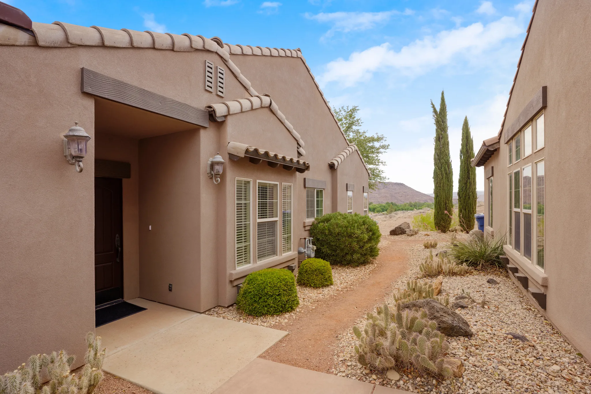 Southwestern-style exterior featuring a tile roof, stucco finish, and an inviting entry with dual sconces