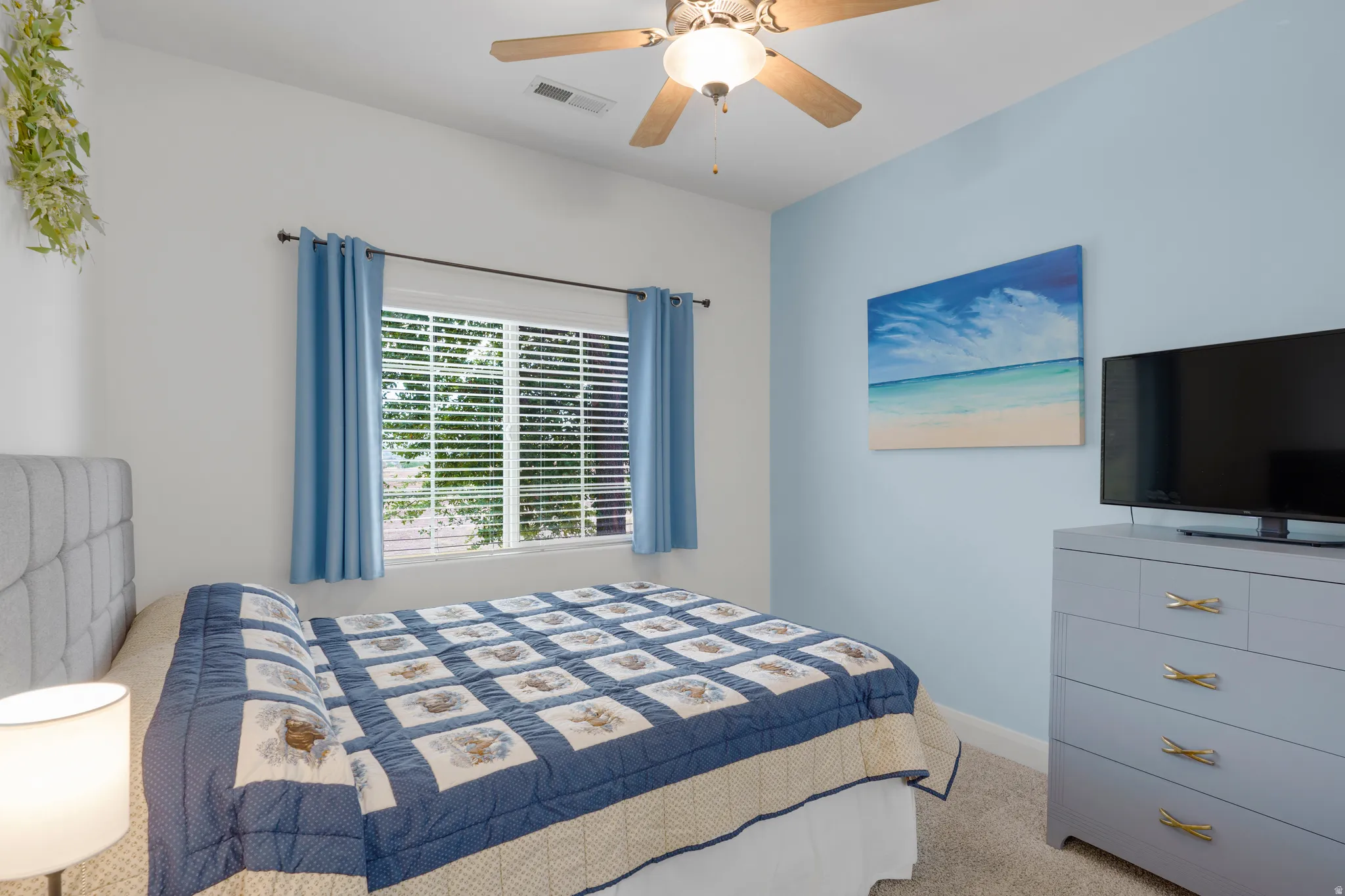 Bedroom featuring a window with blinds, ceiling fan with light fixture, carpeted flooring, and a light blue accent wall