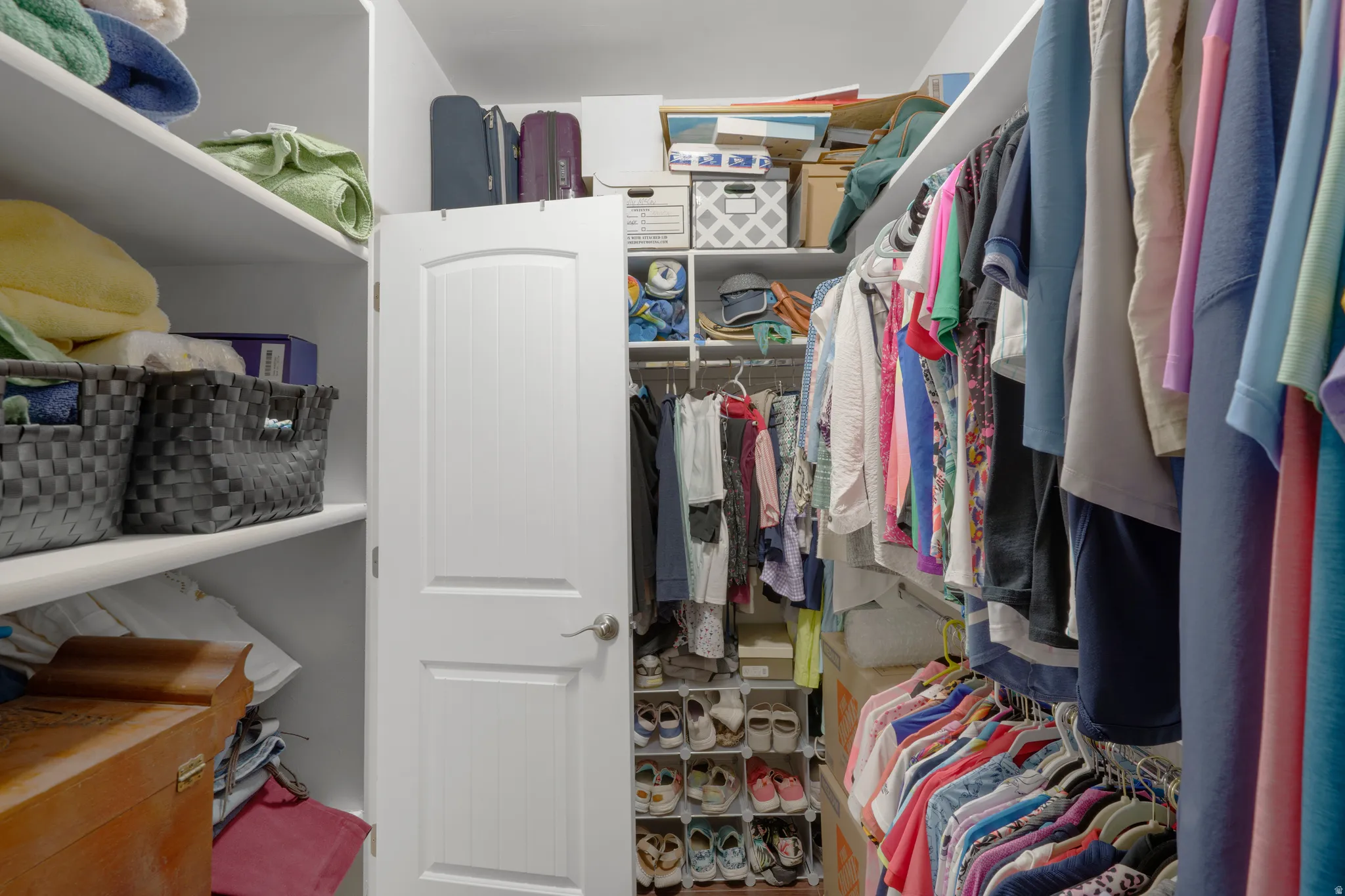 Walk-in closet featuring extensive built-in shelving, multiple hanging rods, and a white panel door