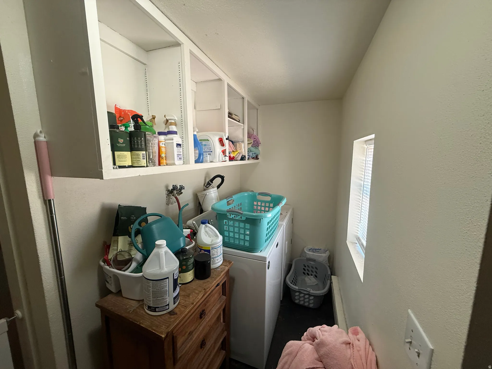 Laundry area featuring upper open shelving, a white washer, and a small rectangular window with blinds