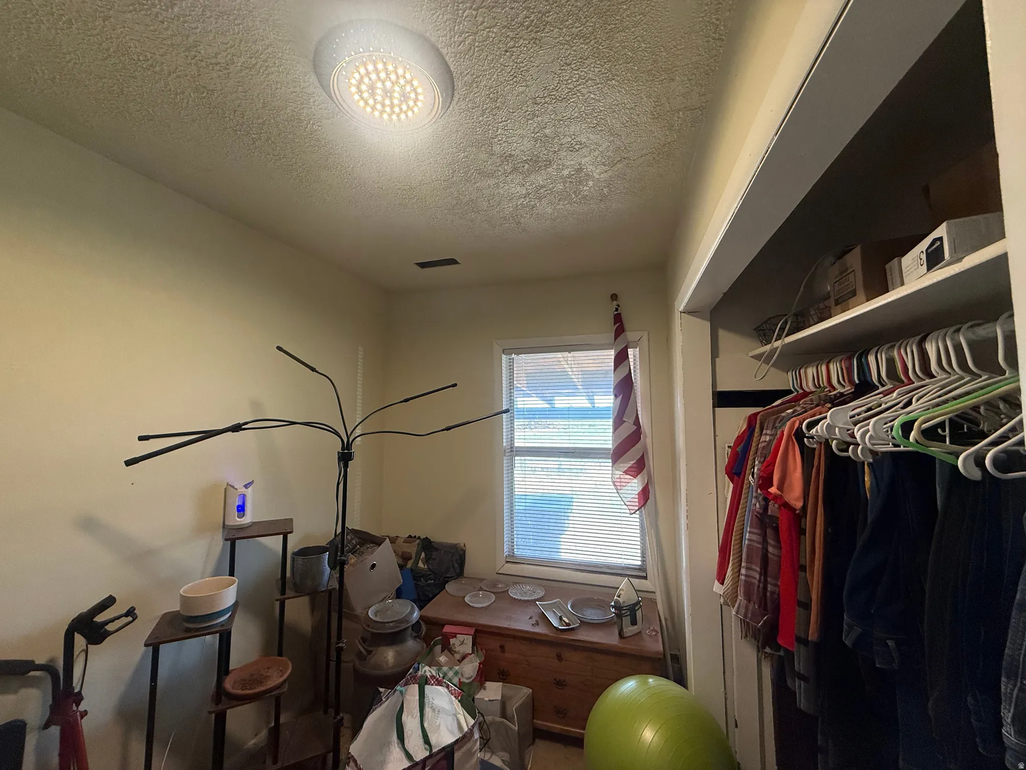 Recessed ceiling lighting, textured ceiling, single window with blinds, built-in closet shelving, and clothes hanging rod