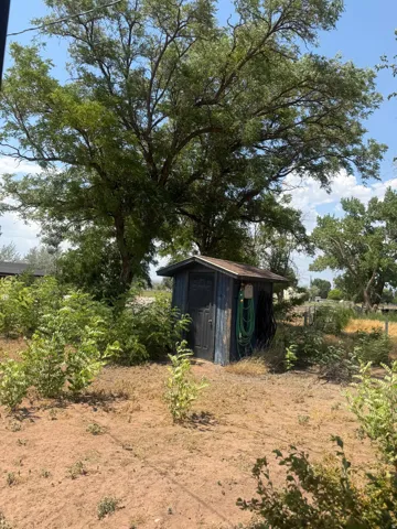 Detached storage shed featuring a wood-finish door and a shingled roof