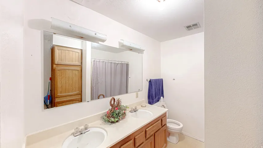 Bathroom featuring a dual vanity with integrated sinks, wood-finish cabinetry, and a full-width mirror