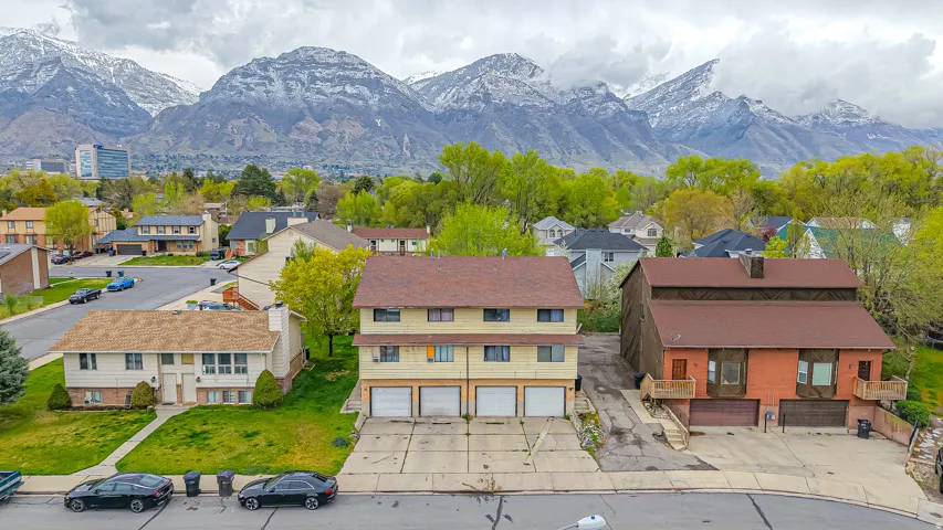 Multi-unit property featuring a brown shingle roof and three garage doors