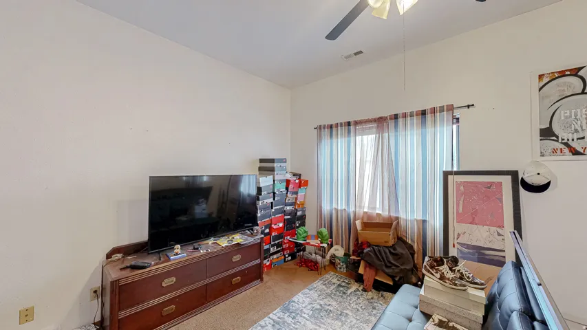 Room featuring light neutral wall paint, a window with striped curtains, and a ceiling fan with integrated lighting