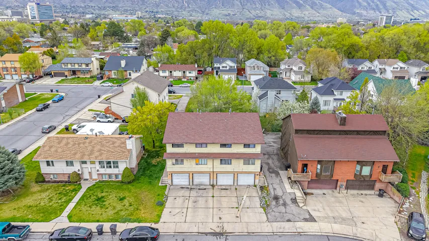 Multi-unit property featuring a brown shingle roof and three garage doors