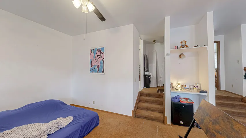 Interior space featuring light-toned walls, a ceiling fan with integrated lighting, and carpeted flooring