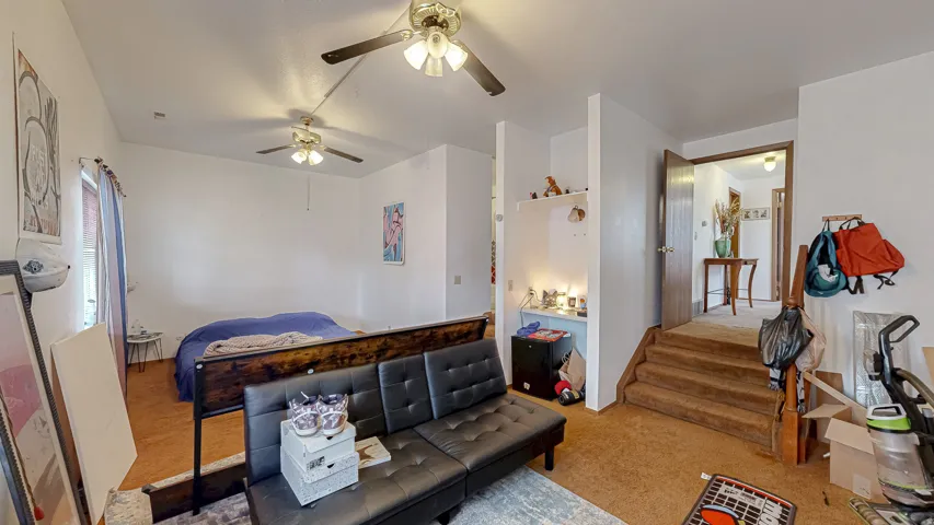 Carpeted interior space featuring white walls and multiple ceiling fans